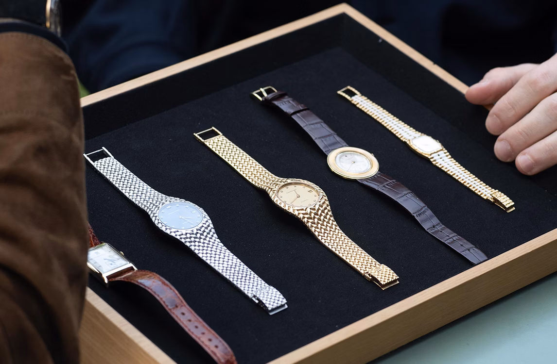 Wooden tray displaying four vintage Audemars Piguet watches with mesh and leather straps: Mini Bamboo, Cobra, Discovolante, and Art Deco Jumping Hour.