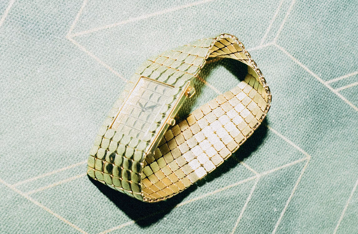 Audemars Piguet Cobra watch: a gold bracelet watch with a woven mesh strap coiled on a teal patterned surface.