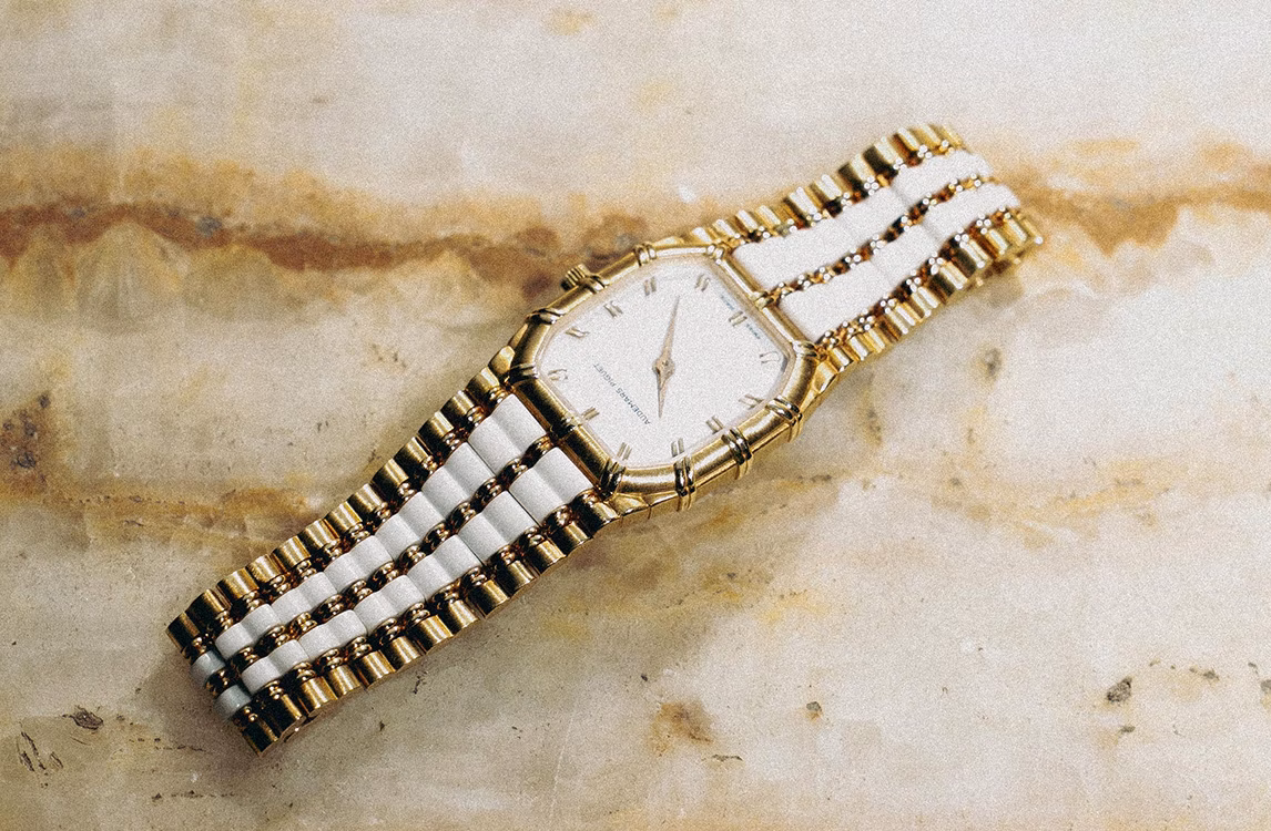 Audemars Piguet Bamboo watch: a gold Audemars Piguet watch with a white ceramic and gold link bracelet on a marble surface.