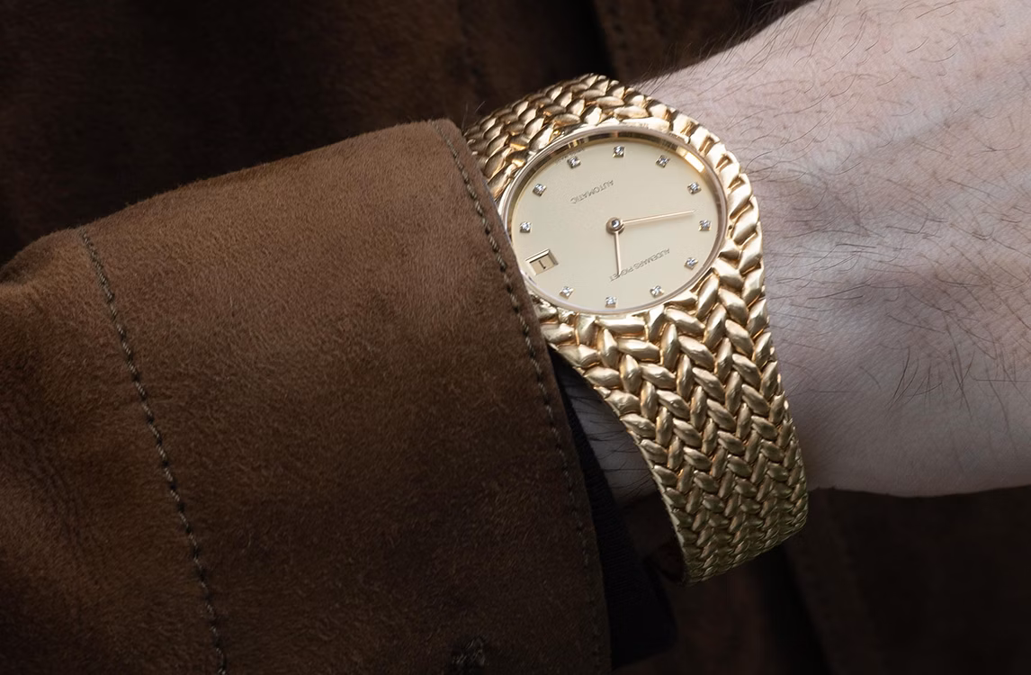 Audemars Piguet Cobra watch: close-up of a gold automatic watch with diamond markers on a wrist, brown suede sleeve.