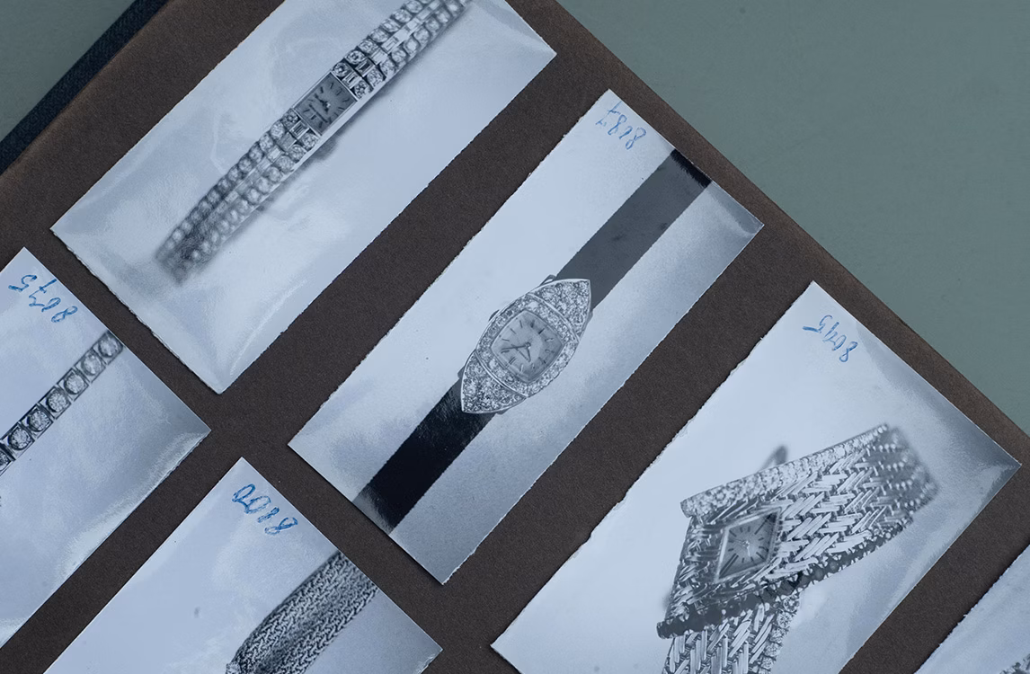 Vintage black and white photographs of diamond and gold watches mounted on an album page.