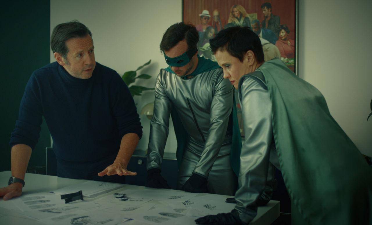 François-Henry Bennahmias y dos superhéroes trabajando en un escritorio.