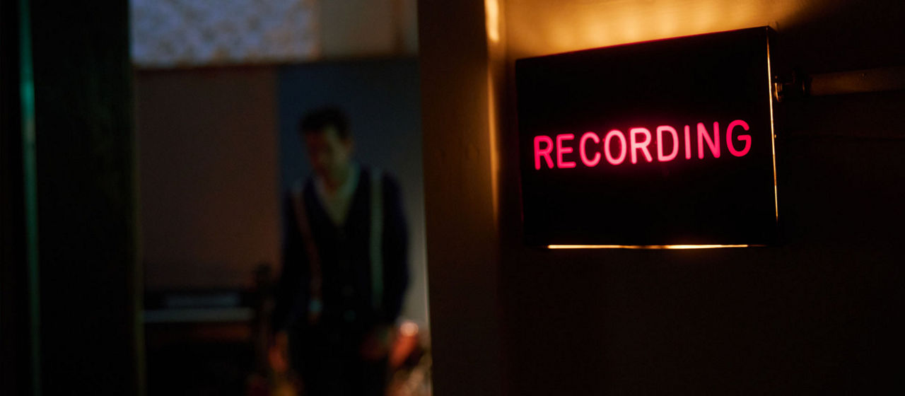 A "Recording" sign on the open door of a recording studio