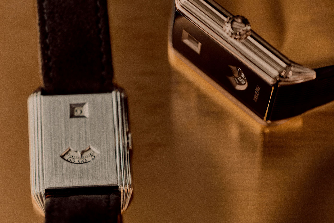 Audemars Piguet Neo Frame Jumping Hour watch: close-up of the case back and a black dial edge on a warm gold-toned surface.