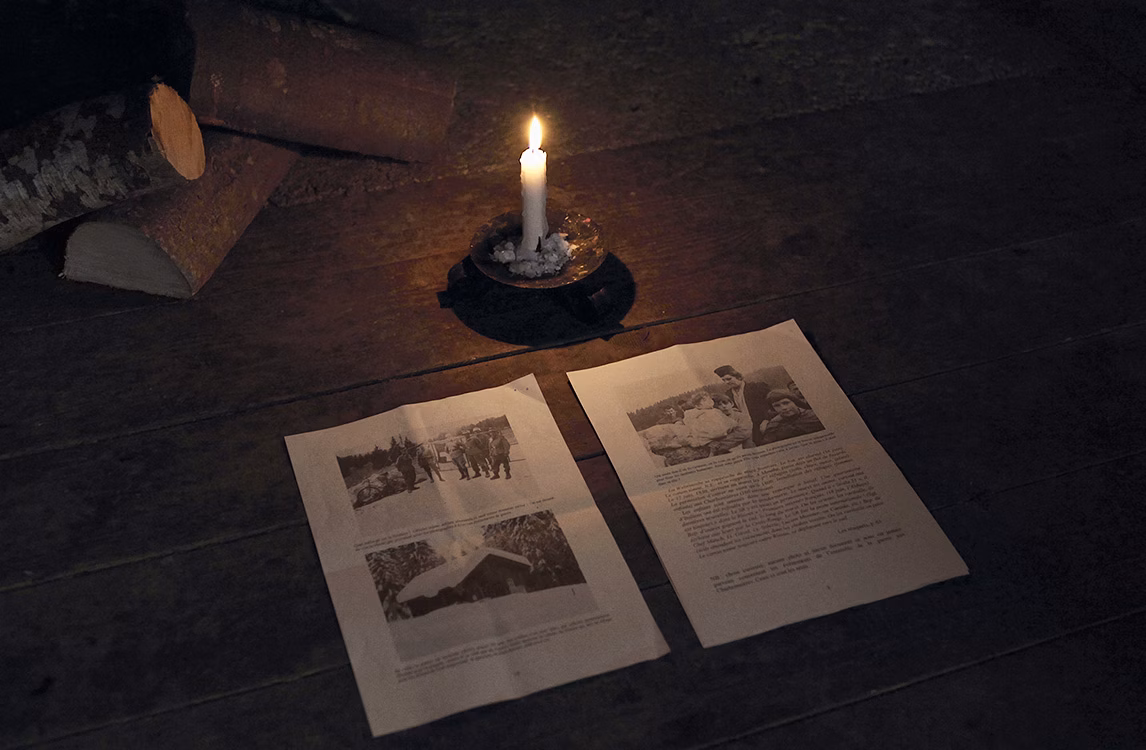 Due fogli di un articolo posati a terra e illuminati da una candela che illustrano Voyage di Arin Rungjang