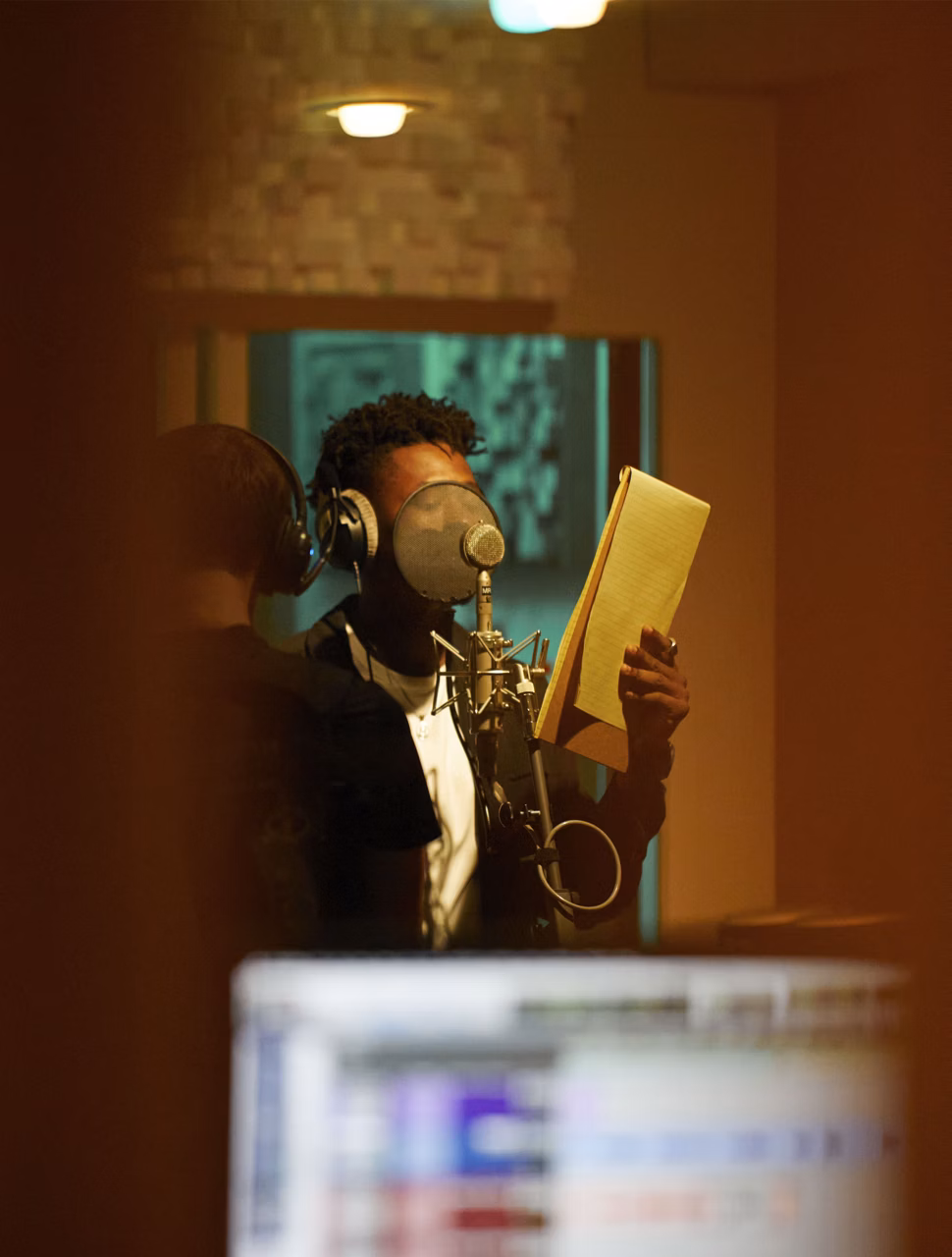 Lucky Daye che canta con un taccuino in mano in uno studio di registrazione