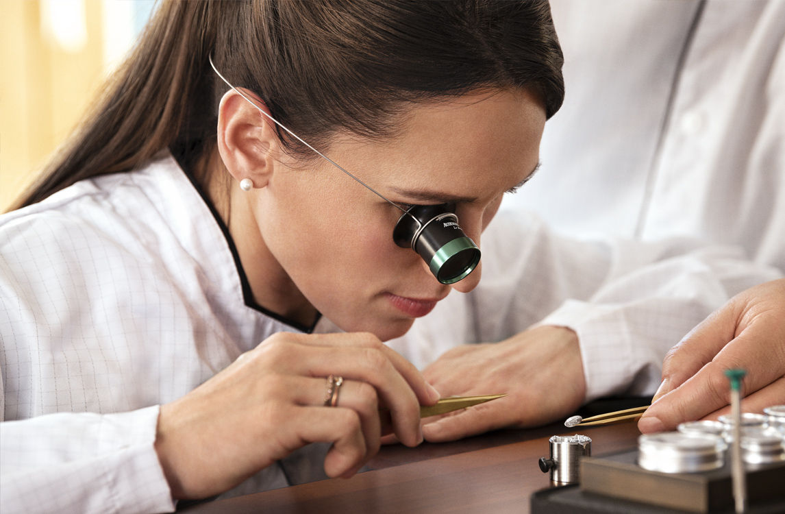 時計師の服を着た女性がメカニズムに取り組む様子