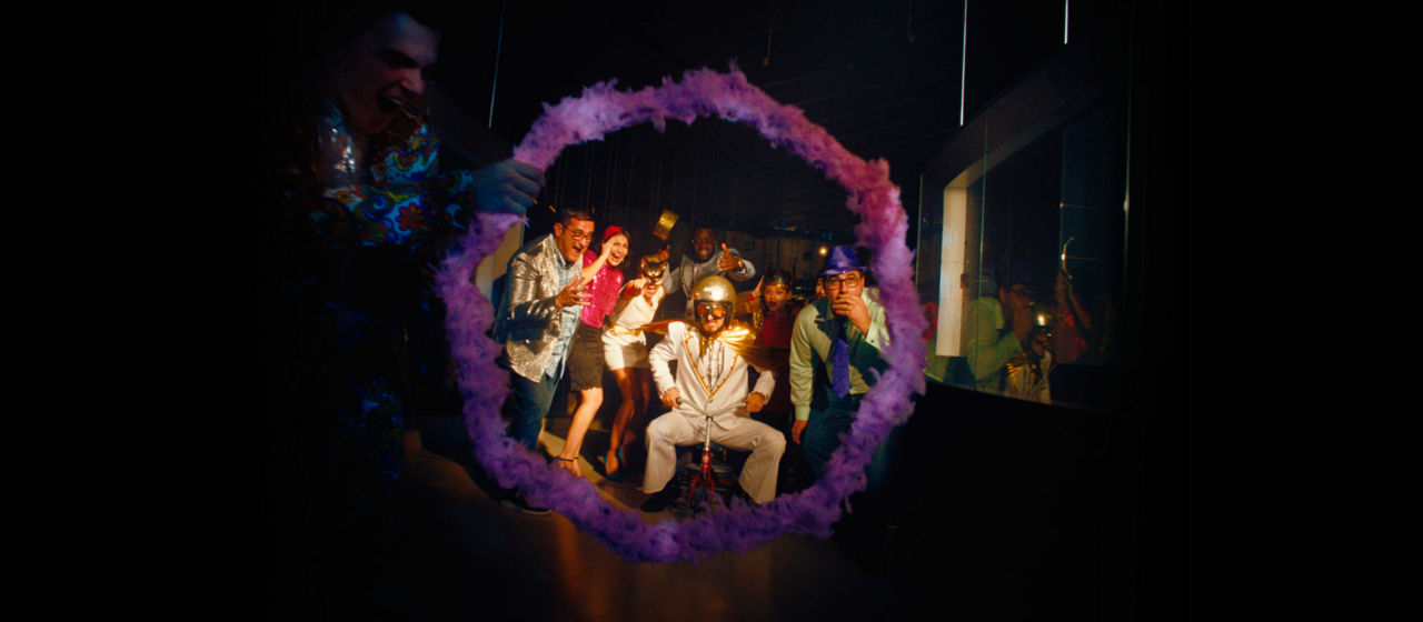 A man on a tricycle ready to jump through an octagonal hoop. 
