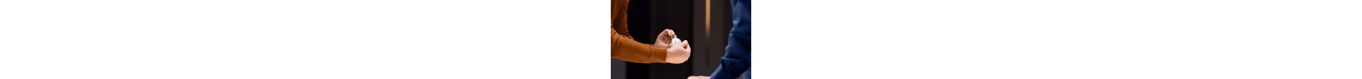 A pair of hands gently holding a timepiece to show it to a client.