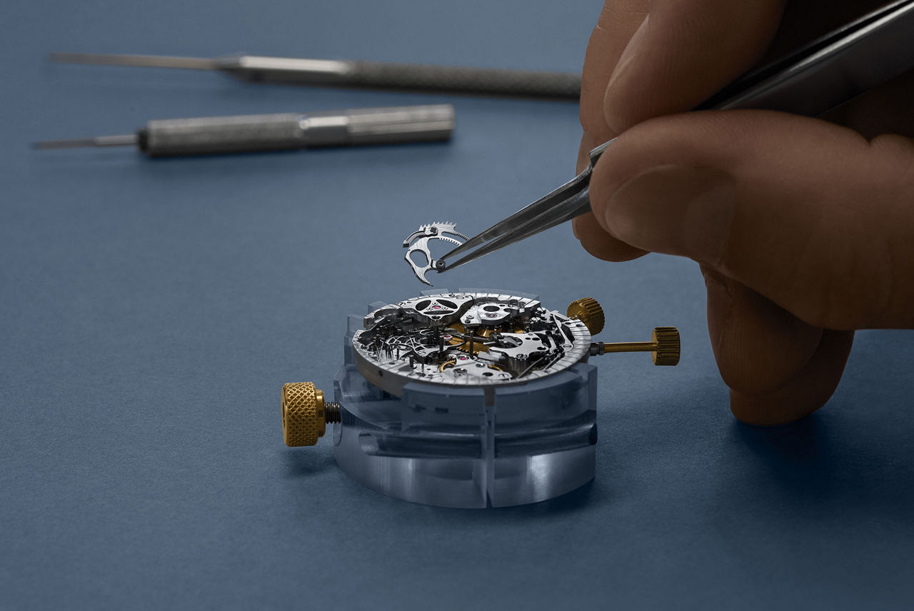 Часовой мастер собирает часовой механизм.