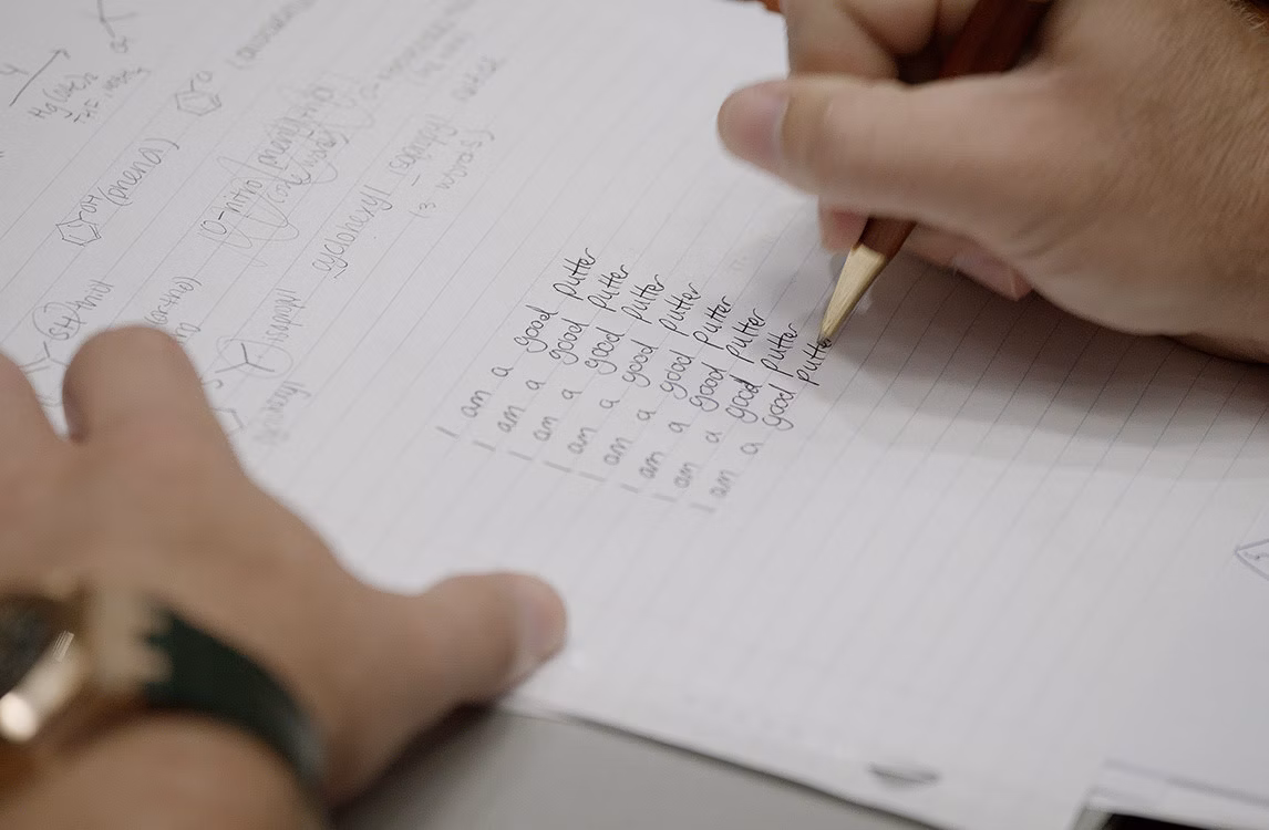 Nahaufnahme der Hand mit den Notizen: „Ich bin ein guter Putter“