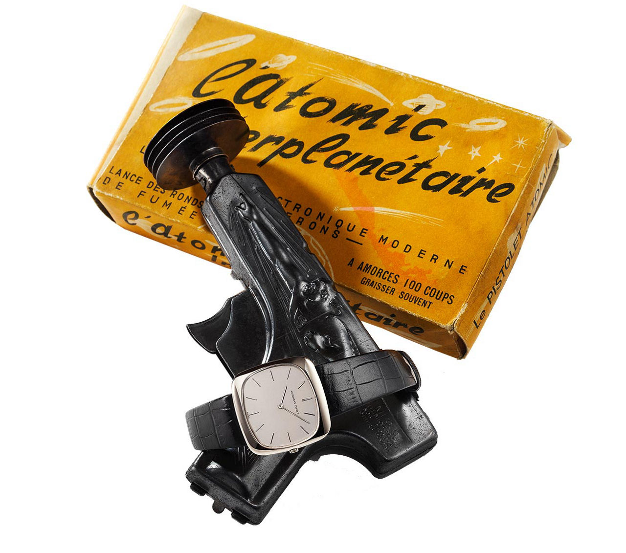 An extra-thin Screen Shape Model 5451 in white gold around a metal gun and its cardboard box